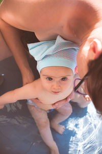 Mother holding baby girl first time in swimming pool. summer activities.