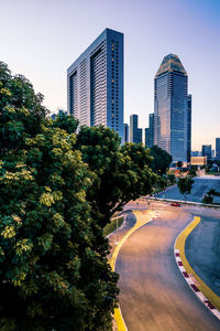 Trees and modern buildings against clear sky