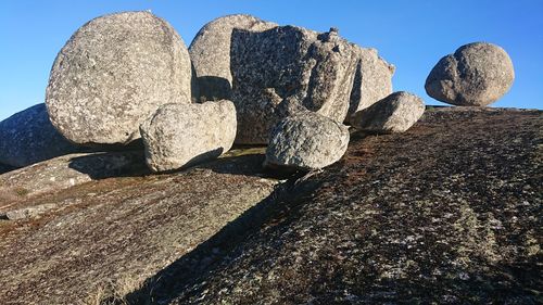 Low angle view of stones on rock against sky