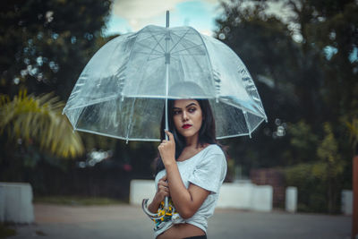 Portrait of a beautiful young woman standing in rain