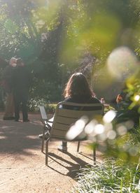 Rear view of people sitting on bench in park