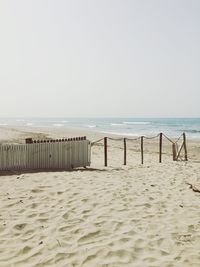 Wooden posts on beach against clear sky