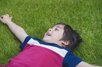 Low angle view of boy lying on grassy field