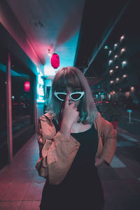 Woman wearing sunglasses standing at night