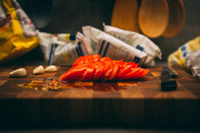 Cooking and home concept - close up of male hand cutting tomato on cutting board with sharp knife