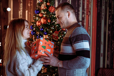 Rear view of couple holding christmas tree