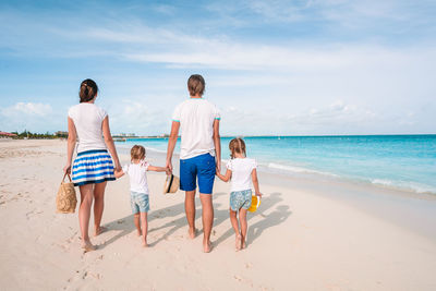 Rear view of people on beach against sky