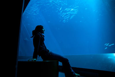 Woman sitting in aquarium 