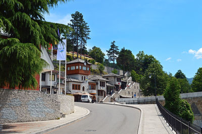 Street amidst houses and trees against sky