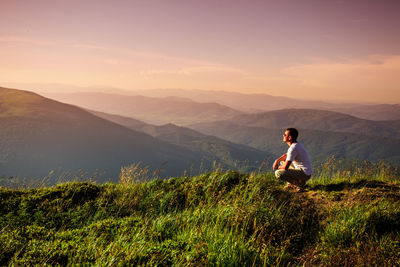 Woman sitting on street amidst mountains against sky