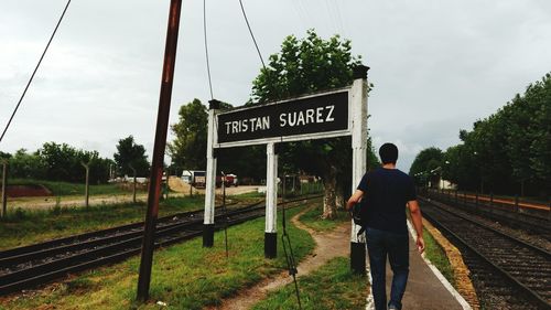 Rear view of man walking on grass against sky