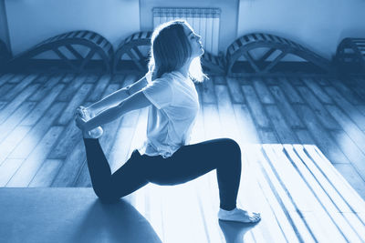 Side view of woman exercising on hardwood floor