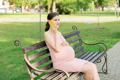 Portrait of woman sitting on bench in park