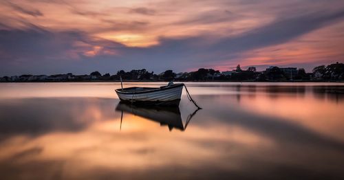 Boats in sea at sunset