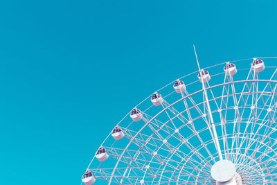 Low angle view of ferris wheel against clear blue sky