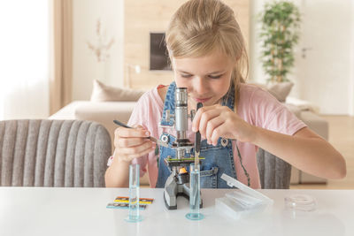Girl looking through microscope at home