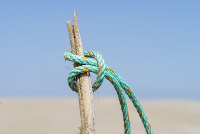 Close-up of rope tied on metal structure against sky