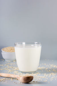 Sesame milk in a glass and seeds in a bowl on the table. dairy alternative. vertical view