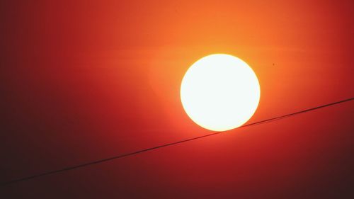 Low angle view of illuminated sun against orange sky