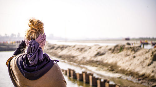 Rear view of woman at beach against clear sky