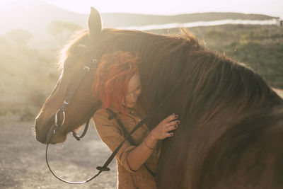 Woman embracing horse on field