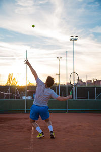 Full length of young man playing tennis on field