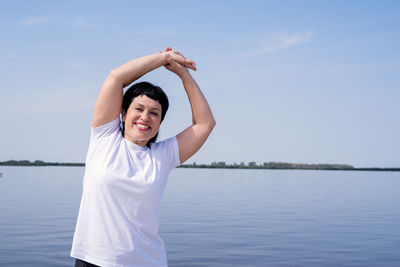 Full length of smiling man standing in lake against sky