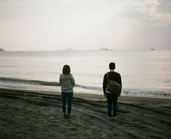 Rear view of man and woman standing on beach