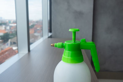 Close-up of green bottle on table against window