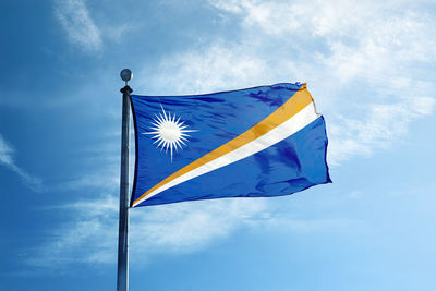 Low angle view of flag against blue sky