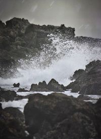 Waves splashing on sea against sky