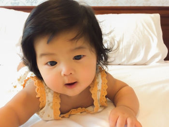 Close-up portrait of cute girl relaxing on bed at home