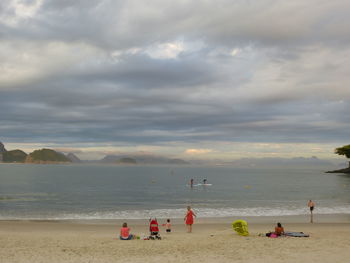 View of people on beach against cloudy sky