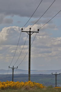 Electricity pylon on field against sky