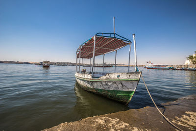 Sailboat moored on sea against clear blue sky