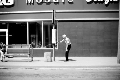 Full length side view of a man walking against building