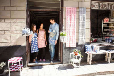 Man and women wearing aprons talking while standing at entrance of fabric shop