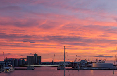 Sailboats at harbor against orange sky