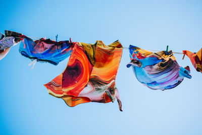 Low angle view of clothes drying against clear blue sky