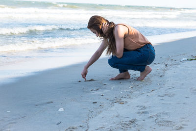 Full length of woman carving on sand at beach