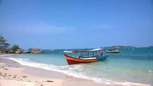 Boat moored on beach against sky