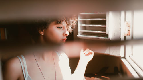 Portrait of young woman looking through window