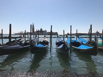 Boats moored in sea against clear sky