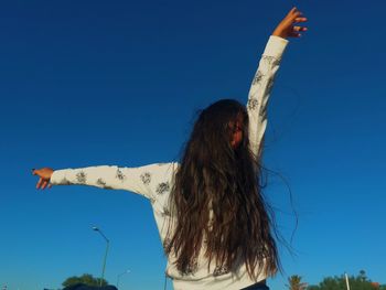 Low angle view of woman against clear blue sky