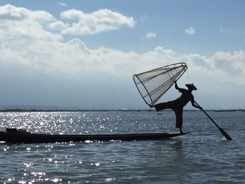 Silhouette man fishing in sea against sky 