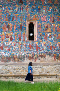 Rear view of woman standing by wall