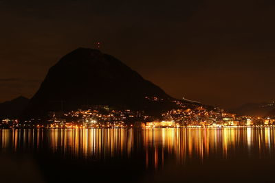 Scenic view of illuminated bay against sky at night