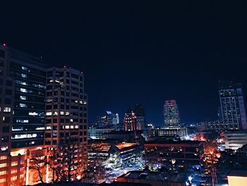 Illuminated cityscape against sky at night