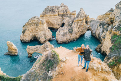 Friends standing on cliff against sea