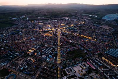 High angle view of illuminated city against sky during sunset